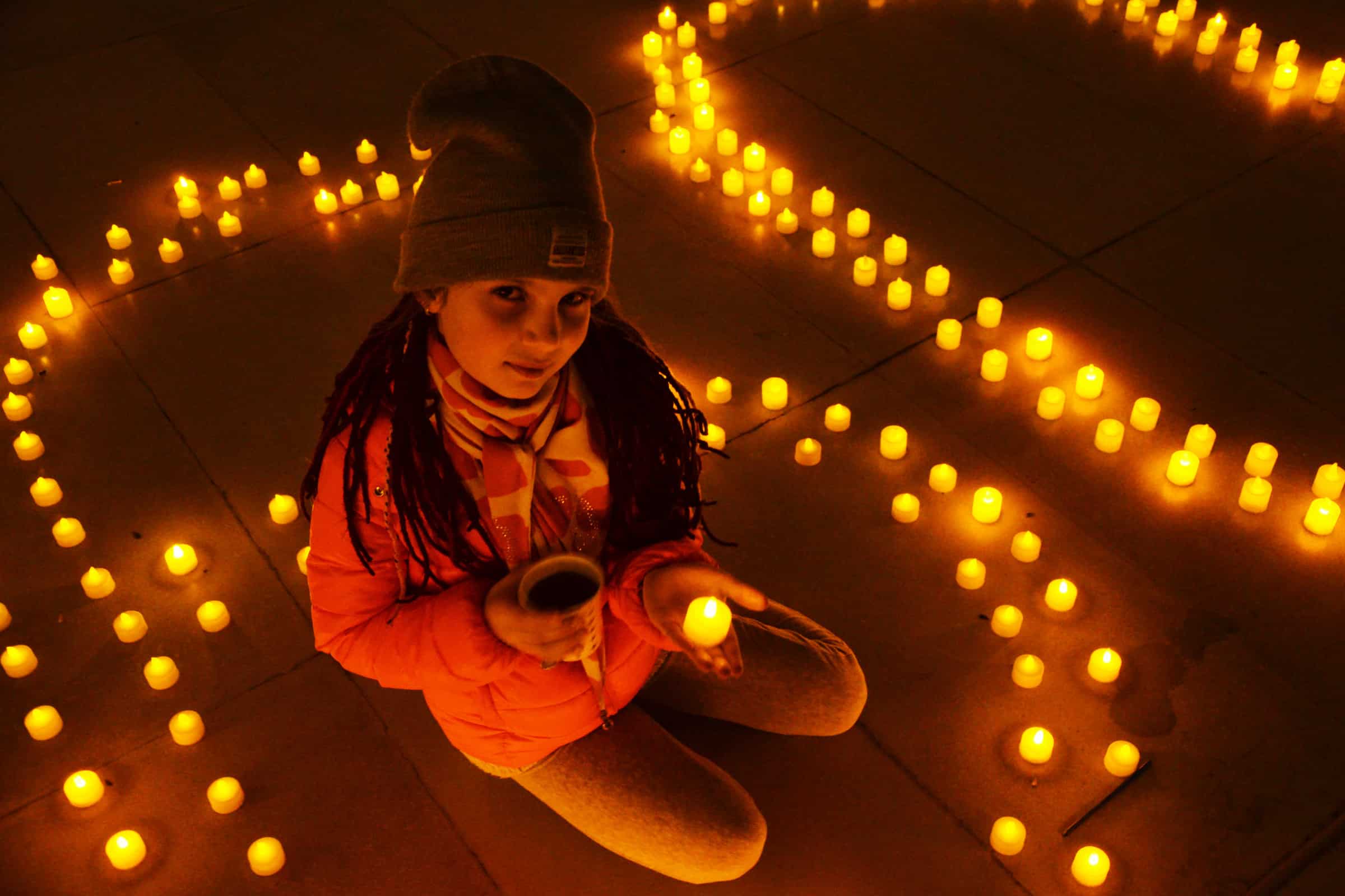 Ein Mädchen feiert die Earth Hour inmitten von Kerzen