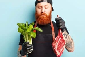 rotbärtiger Mann mit Gemüse und Fleisch in der Hand (c) AdobeStock WayHomeStudio rotbärtiger Mann mit Gemüse und Fleisch in der Hand