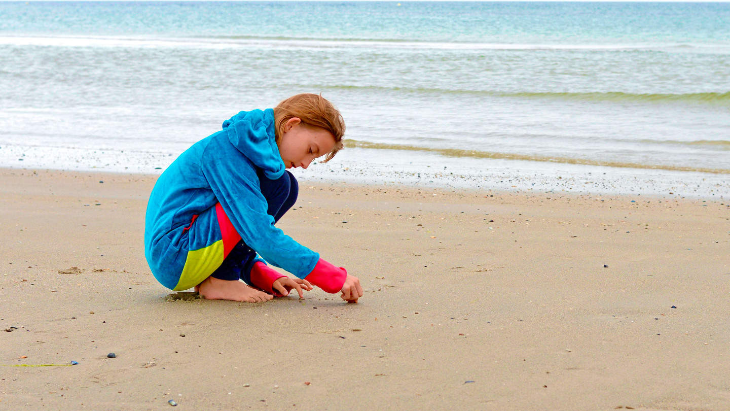 Kind spielt Solitaer im Sand