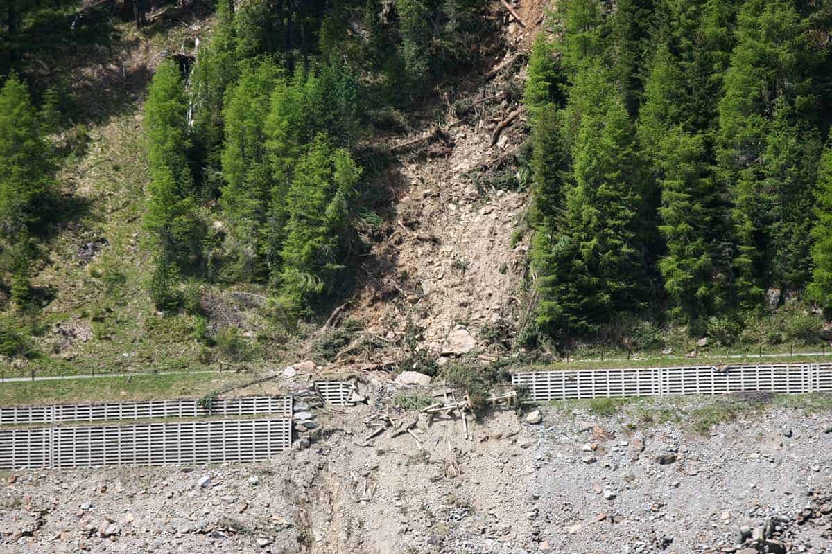 In der Bildmitte sieht man einen Hangrutsch im Tiroler Kauenrtal. Das Geröll hat eine Sicherung durchbrochen. Links und rechts im Bild sieht man Wald.