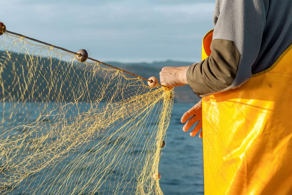 Fischer mit Fischernetz auf Boot